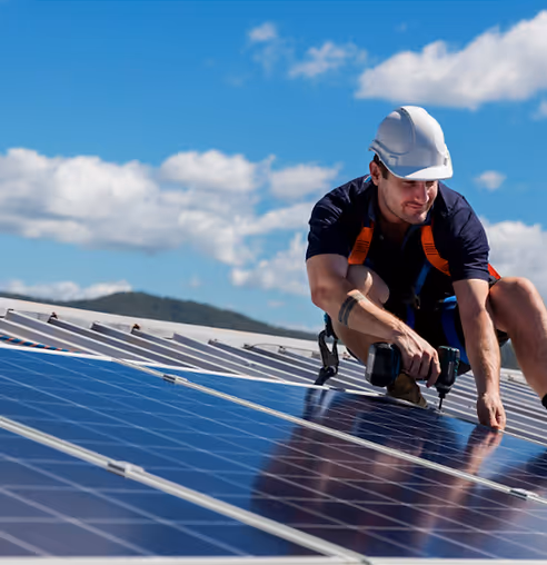 Artisan installant des panneaux solaires sur un toit sous le soleil
